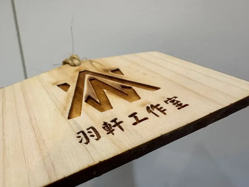 木材雷射雕刻文字與切割外觀，邊緣呈現自然碳化效果